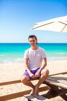 Young man on tropical beach vacation in outdoor cafe photo