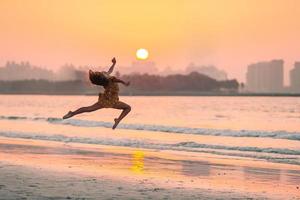 Adorable happy little girl on white beach at sunset. photo