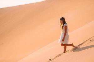 Girl among dunes in desert in United Arab Emirates photo