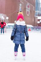 Adorable little girl skating on the ice rink outdoors photo