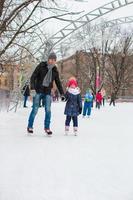 Adorable little girl and happy dad on skating rink outdoor photo