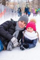 Adorable little girl and happy father on skating rink outdoor photo