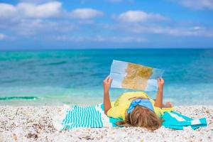 Adorable little girl with map of island on tropical beach photo