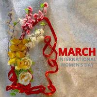 Figure 8 made of ribbon and artificial flowers for International Women's Day celebration on silver background with space for text photo
