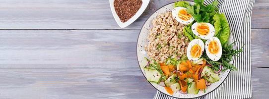 Breakfast bowl with oatmeal, zucchini, lettuce, carrot and boiled egg. Fresh salad. Healthy food. Vegetarian buddha bowl. Banner. Top view photo