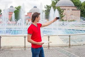 Young man using cell phone with map walking in big city photo