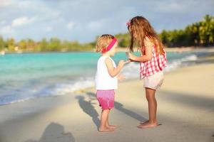 Adorable little girls have fun on white beach during vacation photo