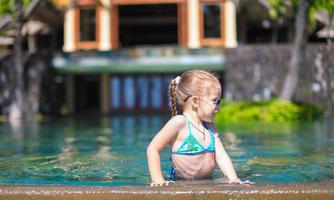 Little cute happy girl in swimming pool during summer vacation photo