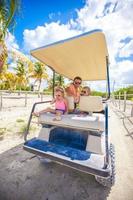 Dad and his little daughters driving golf cart on tropical beach photo