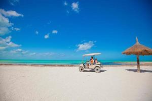 Dad and his little girls driving golf cart on tropical beach photo