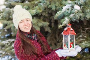 Young beautiful happy woman with red Christmas lantern in the snow photo