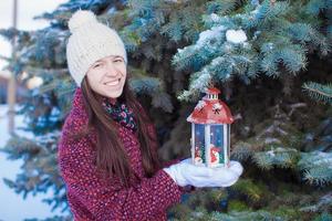 Young beautiful happy woman with red Christmas lantern in the snow photo