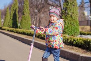 Adorable little girl have fun on the scooter outdoor photo