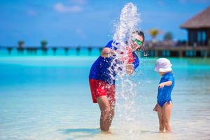 Happy father and little daughter have fun on tropical beach photo