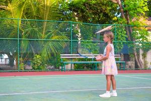Little girl trying to play tennis on outdoor court photo