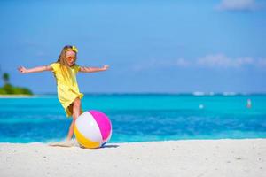 Little adorable girl playing on beach with ball outdoor photo