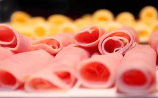 detalle de jamón en rollos con queso fuera de foco en el fondo foto