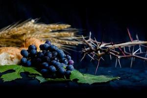 pan de uvas de trigo y corona de espinas sobre fondo negro como símbolo del cristianismo foto