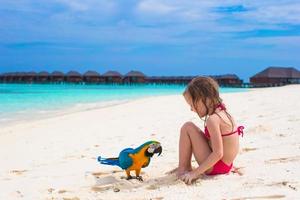 Adorable little girl at beach with big colorful parrot photo