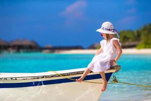 adorable niña feliz y sonriente en un barco en el mar foto