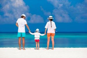 Young family of three on white beach during tropical vacation photo