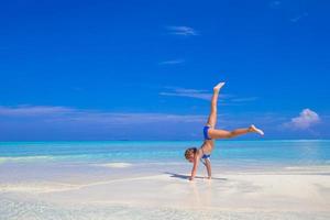 Adorable happy little girl have fun at shallow water on beach vacation photo