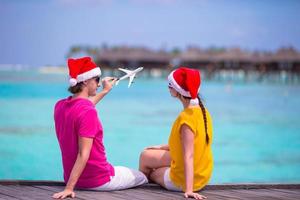 pareja joven con sombreros de santa relajándose en un embarcadero de madera en vacaciones de navidad foto