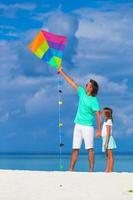 Happy father and little girl flying kite together at tropical beach photo