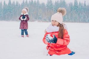 Adorable little happy girls sledding in winter snowy day. photo