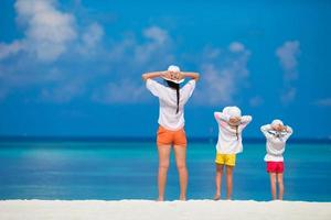 Adorable little girls and young mother on tropical white beach photo