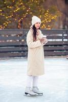 Smiling young girl skating on ice rink outdoors photo