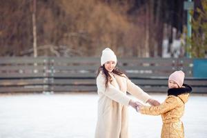 niña adorable con su madre patinando en la pista de hielo foto