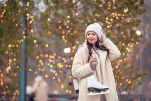 Smiling young girl skating on ice rink outdoors photo