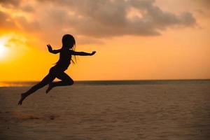 adorable niña feliz en la playa blanca al atardecer. foto