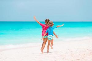 Little girls having fun at tropical beach playing together at shallow water photo