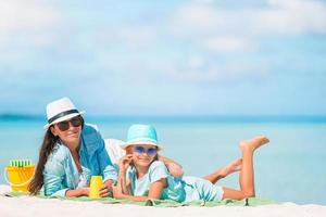 la madre pone crema de protección solar en la pequeña hija en la playa en un caluroso día de verano foto