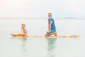 familia de papá y niño en tabla de surf durante las vacaciones de verano foto