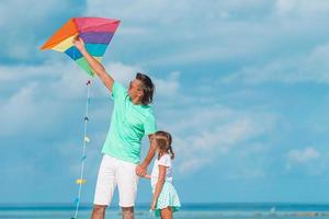 Family flying kite together at tropical white beach photo