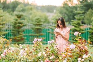 niña en un jardín de flores entre hermosas rosas. olor a rosas foto