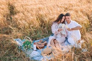 familia joven feliz en picnic en campo de trigo amarillo foto