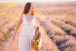 Woman in lavender flowers field in white dress and hat photo