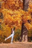 concepto de otoño - mujer hermosa en el parque de otoño bajo el follaje de otoño foto