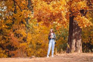 Fall concept - beautiful woman in autumn park under fall foliage photo