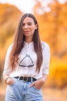 Fall concept - beautiful woman in autumn park under fall foliage photo