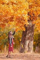 Fall concept - beautiful woman in autumn park under fall foliage photo