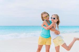 Little girls having fun at tropical beach during summer vacation playing together photo