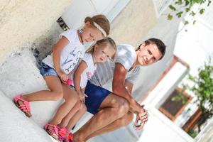 joven padre y su hija sentados en la puerta de una casa antigua en la calle emporio, santorini foto