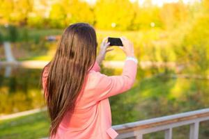 Young woman take a photo by her phone at autumn day