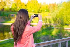 mujer joven toma una foto con su teléfono en el día de otoño