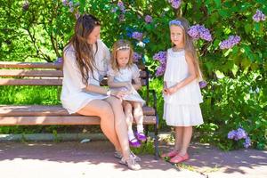 Mother and adorable girls enjoying warm day in lush garden photo